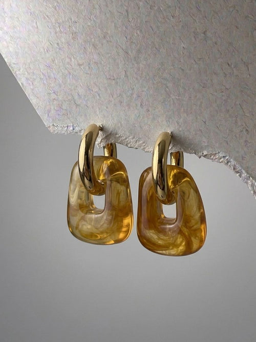 Pair of gold hoop earrings on a textured gray background