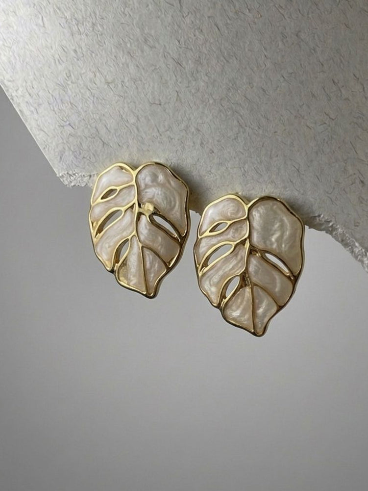 Pair of leaf-shaped earrings on a textured surface
