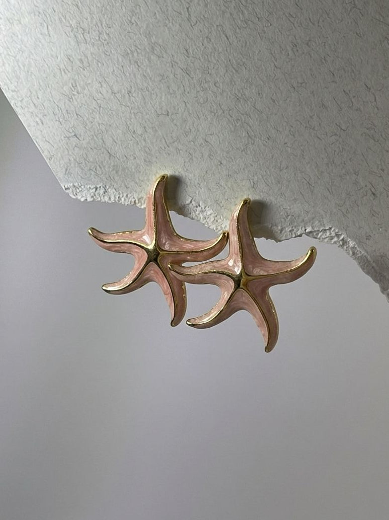 Star-shaped brass earring on a textured white surface