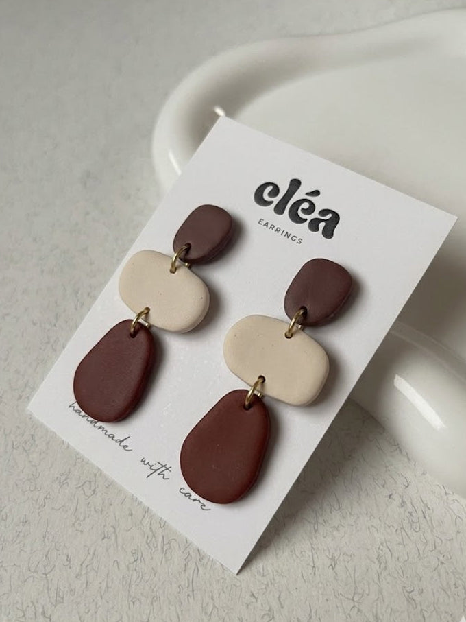 Pair of earrings on a 'cleá' branded card against a light background