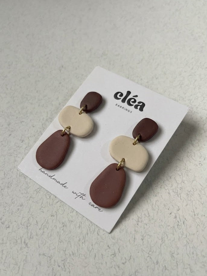 Pair of earrings on a 'cléa' branded card against a light background