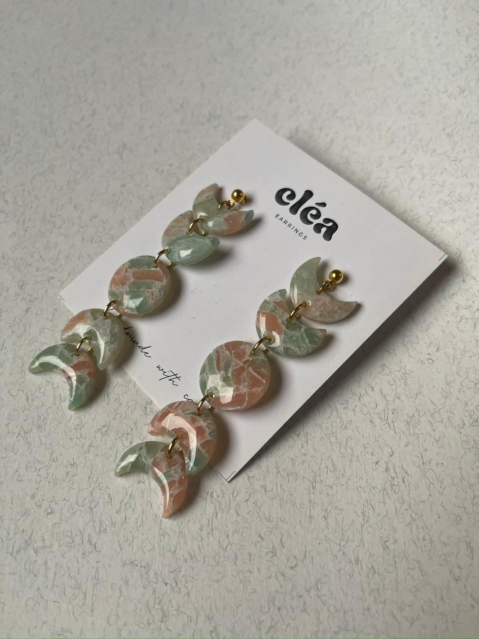 Pair of earrings on a card with 'Clea' branding against a light background