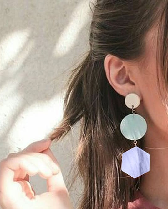 Close-up of a person wearing colorful earrings with a neutral background